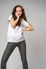 Beautiful young girl posing in white T-shirt and jeans on gray background - 788463630
