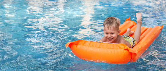 Cute little boy exudes joy as he floats in a pool on a colorful inflatable mattress