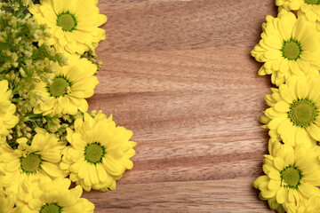 Bouquet of yellow flowers, lying as a decoration on both sides of a wooden surface, space for text