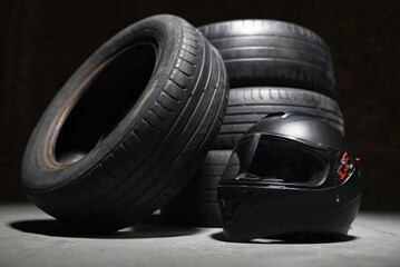 Old used transport car tyres and racer helmet on dark background. Motorsport concept. Rally.