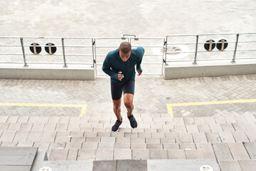 Running, energy and fitness man at stadium steps for workout, resilience or training challenge....