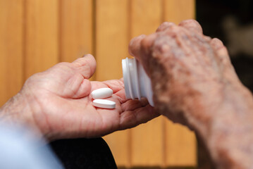 Medicine,senior woman hand pouring 2 white pills to another hand,Daily norm of vitamins, modern pharmacy for body and mental health concept