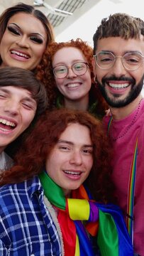 Vertical HD portrait of lovely group of young activist for LGBT rights smiling at camera with rainbow flag,. Diverse people of gay and lesbian community laughing celebrating gay pride month.