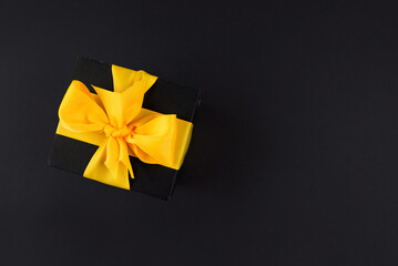 Top view photo of black gift box with ribbon wrapped as a bow isolated on black background