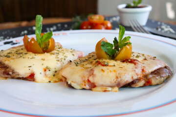 Meat Milanese with cheese covered with melted cheese, topped with cherry tomatoes