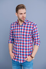 Fototapeta premium Man isolated on grey. Millennial man wearing checkered shirt. Casual style of millennial man. Portrait of young man in casual style shirt. Stylish face portrait of unshaven guy. Model posing