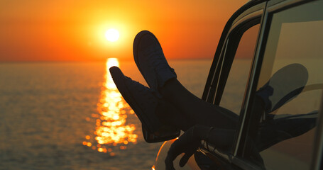 Sunset, beach and feet by window of car on road trip for tropical holiday, vacation or adventure....