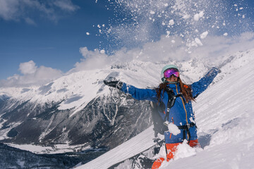 Woman snowboarder riding on slope of powdery snow in high mountains avalanche-prone area. Freeride at ski resort, Snow splashes trail,  mountain peaks view