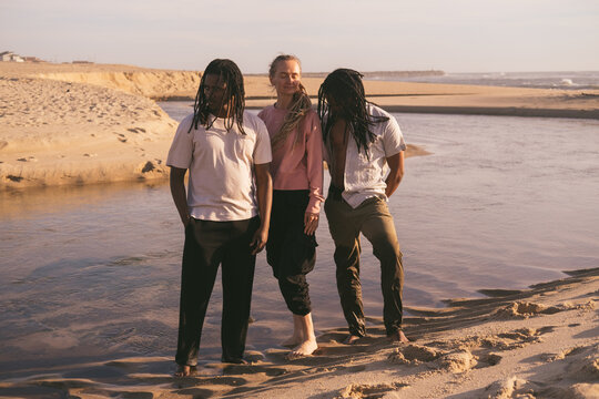 Dread hairstyle. Portrait of two African men and caucasian European woman wearing dreadlocks on ocean posing during sunset