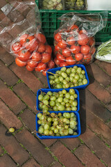 blue plastic containers filled with grapes and two plastic transparent bags filled with tomatoes