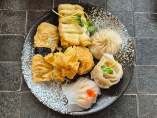 A plate of assorted dumplings and other food items. The food items are of different shapes and sizes.