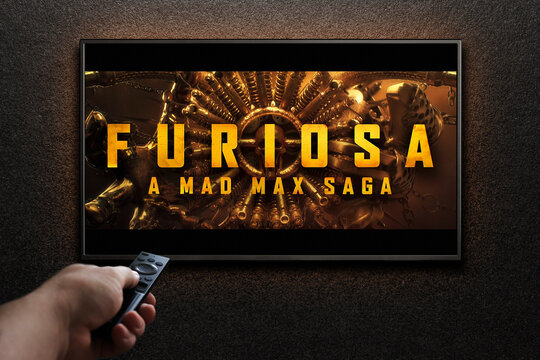 Furiosa A Mad Max Saga trailer or movie on TV screen. Man turns on TV with remote control. Astana, Kazakhstan - March 22, 2024.