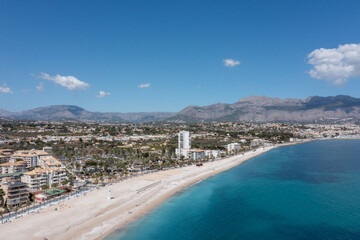 Fototapeta na wymiar Aerial drone photo of the Spanish town of L'Albir in Spain Alicante showing the beach front on a sunny summers day with the Spanish mountains in the background