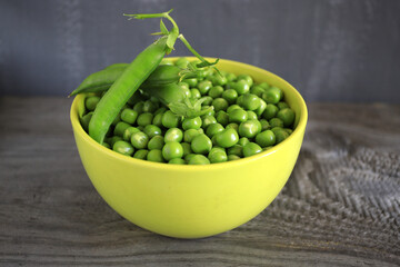 Flat lay composition with green peas in a green plate on wooden background