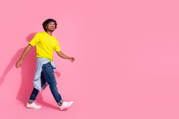 Photo of funny cool cheerful man wear trendy yellow clothes going looking empty space isolated on pink color background