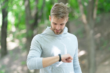 Man tracking fitness results dressed in sportswear outdoor. Man runner with fitness gadget. Smartwatch for fitness. Sporty fit man with sport equipment checks time on smartwatch. Check running time - 788519226