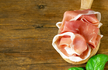 prosciutto ham on a wooden board with basil - 788519403