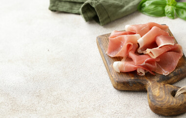 prosciutto ham on a wooden board with basil - 788519650