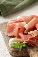 prosciutto ham on a wooden board with basil