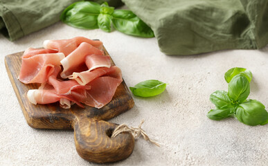 prosciutto ham on a wooden board with basil