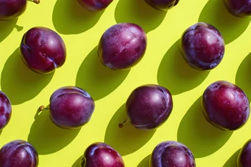 Plexiglas foto achterwand Fresh purple plums arranged on a vibrant yellow background, top view, flat lay composition with copy space © SHOTPRIME STUDIO