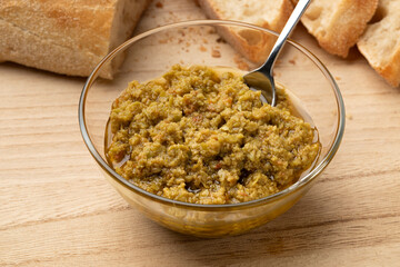 Glass bowl with traditional homemade green olive tapenade close up