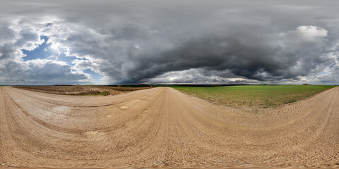 hdri 360 panorama on wet gravel road among fields in spring nasty day with storm clouds in equirectangular full seamless spherical projection, for VR AR virtual reality content