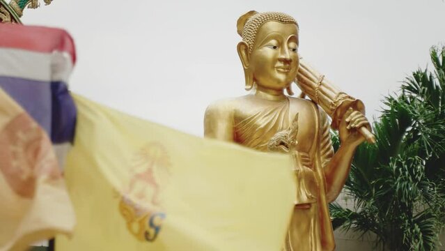 Golden Buddha statue and Royal Flag of Thailand moving on the wind.