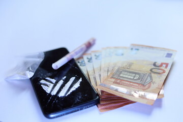 cocaine lines on a smartphone , with banknotes on white background - obrazy, fototapety, plakaty