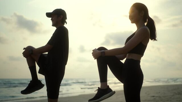 
Couple young two friends stretching leg before running at seaside. Young couple wearing sportswear running on sand sea ocean beach outdoor jog on seaside. Training athlete work out outdoor concept.
