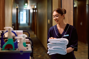 Young chambermaid replenishing towels in guest rooms at  hotel.