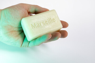 hand holding a Marseille soap bar , isolated white background