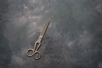 Old metal scissors flat lay on a dark grunge background. Top view, copy space.