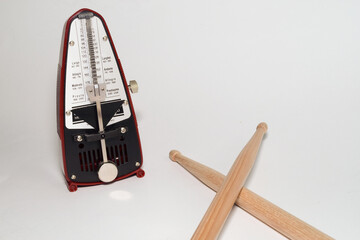a pair of wooden drumsticks and a metronome