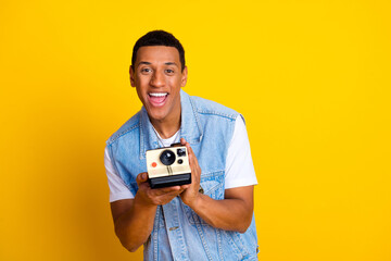Photo of handsome funky guy dressed jeans waistcoat holding retro camera make instant phontoes...