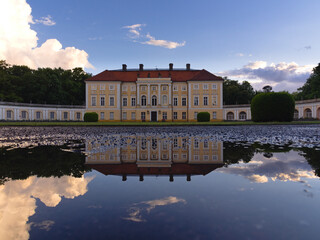Pałac w Pawłowicach na tle błękitnego nieba wraz z odbiciem w kałuży