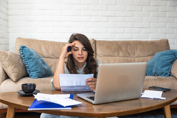 Young stressed woman having issue with utility bills expense, sitting at home trying to calculate...