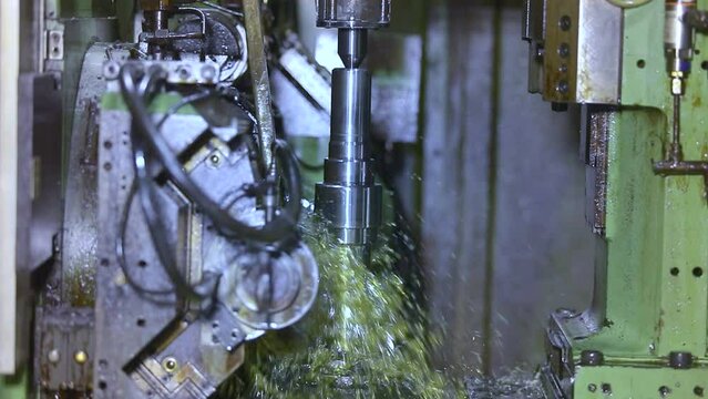 CNC grinding milling machine. CNC turning center. CNC machining high precision turning throwing coolant liquid on metal component during shaping forming process using machining center large workpiece