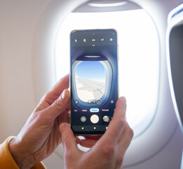 woman taking photos through plane window