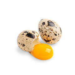 Two whole and broken uncooked raw quail eggs of oval shape with brown spots and speckles with...