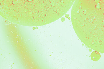 Beautiful cosmetic background. Golden soft green abstract oil bubbles or face serum background. Oil and water bubbles macro photography.