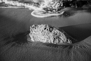 sea, waves, beach, sand and stone at sunset time. black and white photo