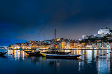 Porto, Portugal old town on the Douro River with traditional rabelo boats at night. With wine...