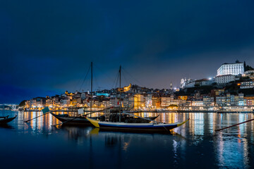 Porto, Portugal old town on the Douro River with traditional rabelo boats at night. With wine...
