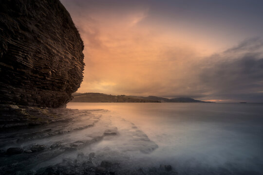 Sunset on the Lastron nudist beach in Zierbena, Bizkaia, with the water between the rocks on the shore