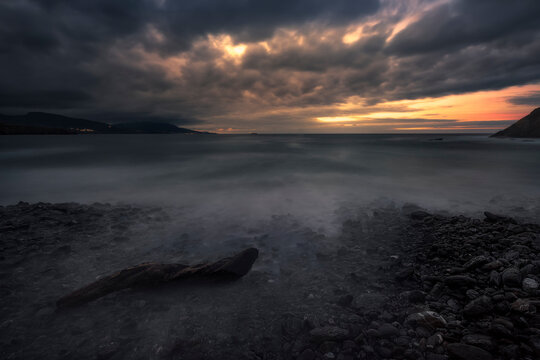 Sunset on the Lastron nudist beach in Zierbena, Bizkaia, with the water between the rocks on the shore