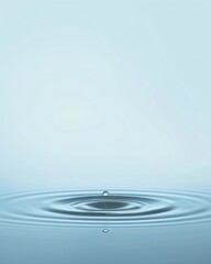 On a blue background, a small drop of water ripples on a calm surface The background is a light blue color with no objects or shadows, creating a serene and clean atmosphere The soft color tones enhan