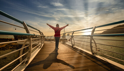 Traveler woman wear red clothes and raising arm standing on Songdo Skywalk at sunset in Busan,...
