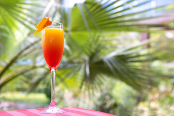 Non-alcoholic cocktail on the background of palm trees. A refreshing drink of red and yellow color....