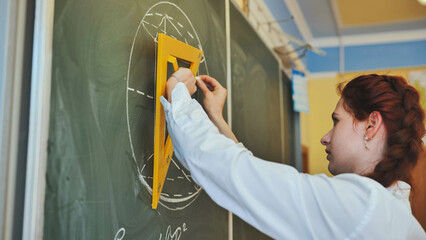 A red-haired schoolgirl draws geometric shapes on the board.